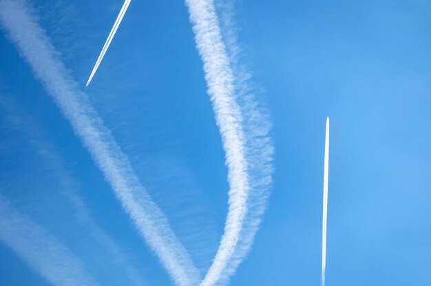 Scie di scie di aeroplani in alto nel cielo blu