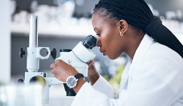 Scienza medica donna nera e microscopio in laboratorio per analisi di ricerca e medicina Donna dottoressa e scienziata studiano al lavoro per un'indagine sanitaria e futuristica o innovazione