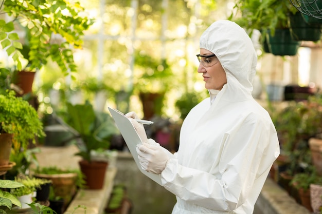 Scienziata che indossa la scrittura del vestito pulito negli Appunti