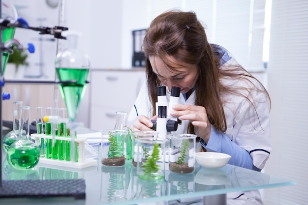 Scienziata che regola il suo microscopio in un laboratorio di biotecnologia. Laboratorio di ricerca. Scienziato accademico.