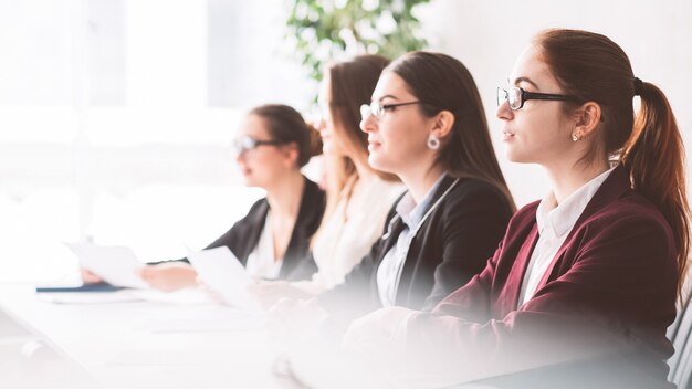 Scienziate al simposio. Donne intelligenti potenti che ascoltano l'oratore alla conferenza scientifica.