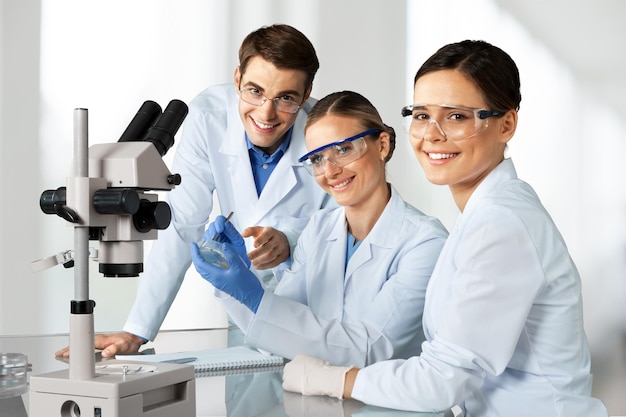 Scienziate e uomini con gli occhiali che lavorano con il microscopio