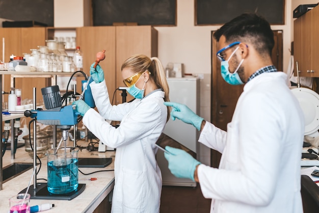 Scienziati e ricercatori di mezza età con maschere protettive per il viso lavorano in laboratorio chimico sul vaccino contro il coronavirus.