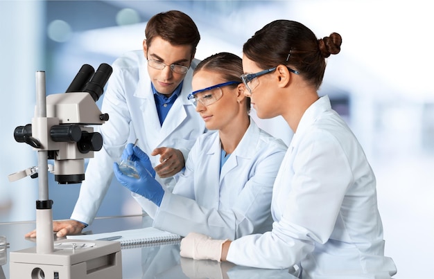Scienziati e scienziati con gli occhiali che lavorano con il microscopio