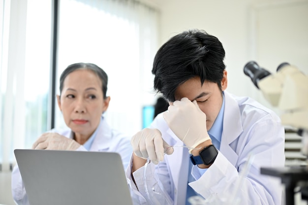 Scienziato asiatico stressato sconvolto dal suo progetto di esperimento mentre lavorava in laboratorio