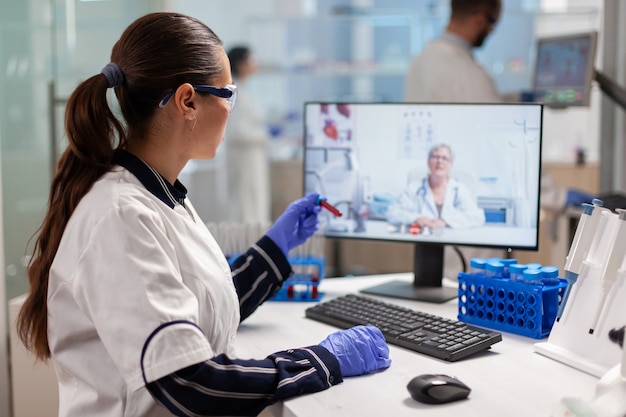 Scienziato che ascolta un medico professionista in videochiamata, durante una riunione virtuale nel laboratorio di ricerca medica