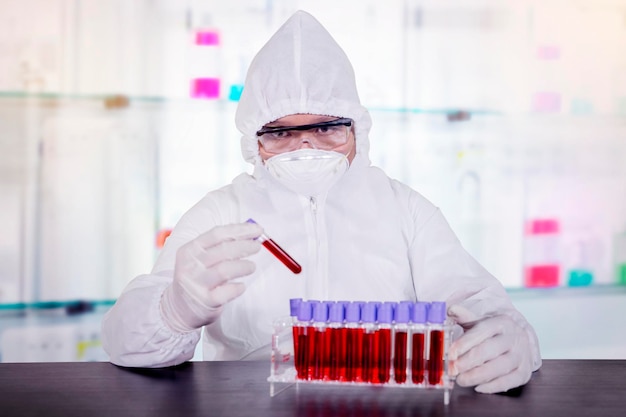 Scienziato che tiene un tubo di sangue dal suo rack in laboratorio