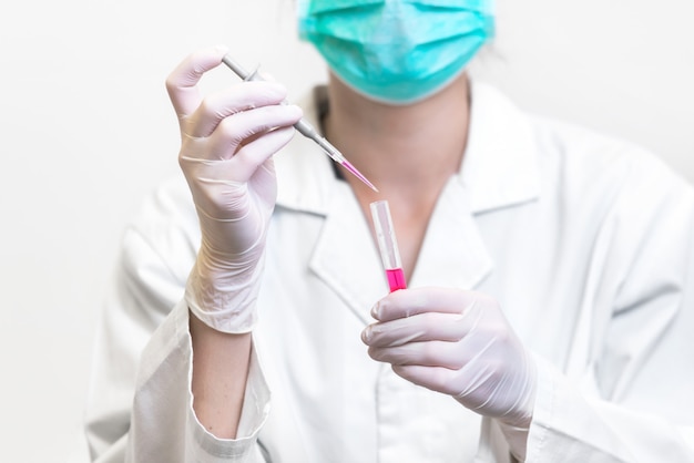 Scienziato della donna irriconoscibile del primo piano che cade liquido colorato in provetta.