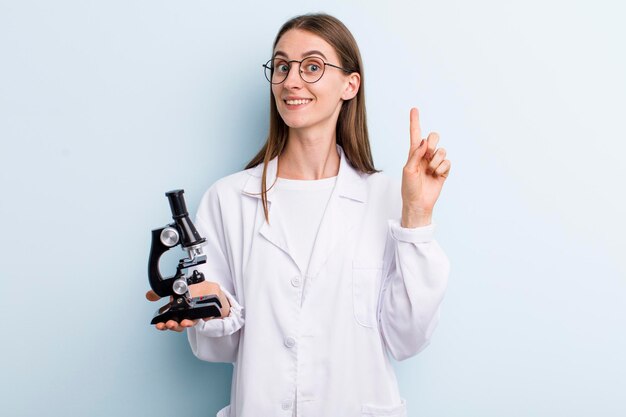 Scienziato della giovane donna graziosa dell'adulto con un microscopio