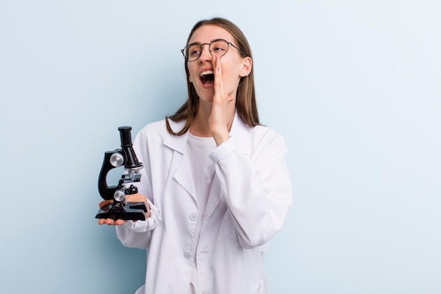 Scienziato della giovane donna graziosa dell'adulto con un microscopio
