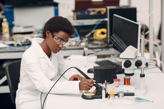 Scienziato donna afroamericana che lavora in laboratorio con saldatore