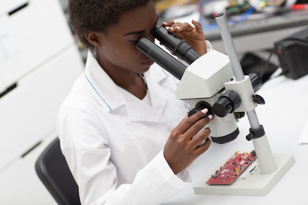 Scienziato donna afroamericana che lavora in laboratorio con tecnologia elettronica
