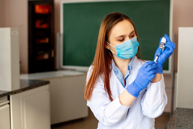 Scienziato in laboratorio che tiene una siringa con vaccini liquidi per bambini o anziani