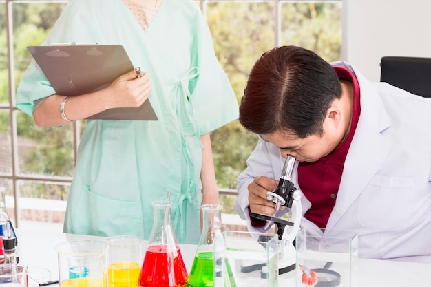 Scienziato maschio senior che osserva tramite un microscopio in un laboratorio.