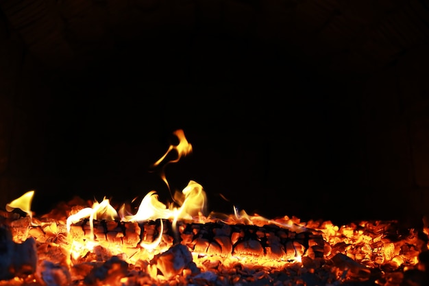 Scintille roventi brucianti volano da un grande fuoco. Bellissimo sfondo astratto sul tema del fuoco. Carboni ardenti, particelle in fiamme che volano via su sfondo nero.