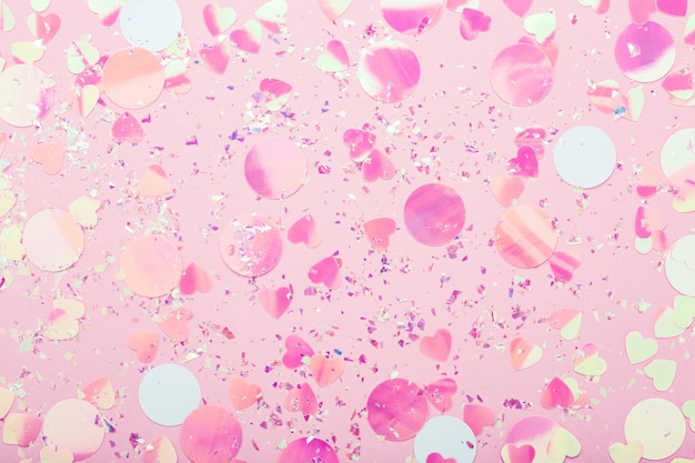 Scintillii glitter festosi e coriandoli colorati sul tavolo rosa