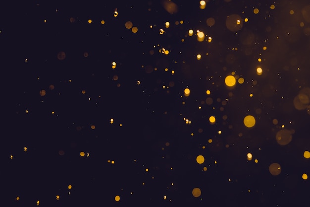 Scintillio astratto scuro del bokeh dell&#39;oro su fondo nero