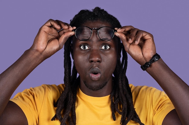 Scioccato uomo afroamericano millenario che rimuove gli occhiali sul primo piano viola