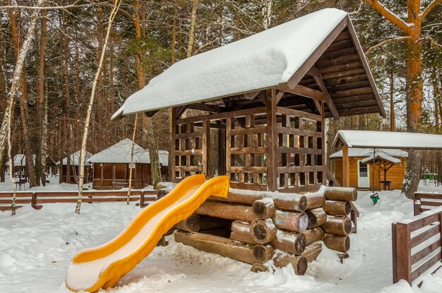 Scivolo per bambini in legno nel parco in inverno.