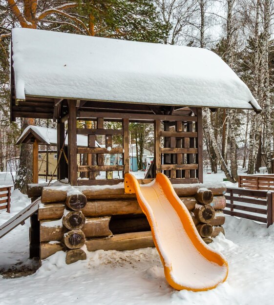 Scivolo per bambini nel parco giochi in inverno nella foresta.