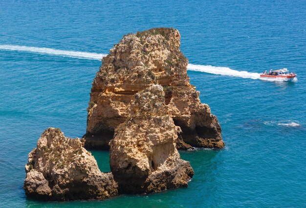 Scogliera gialla vicino alla costa (Ponta da Piedade, Algarve, Portogallo). Tutte le persone in motoscafo sono irriconoscibili.