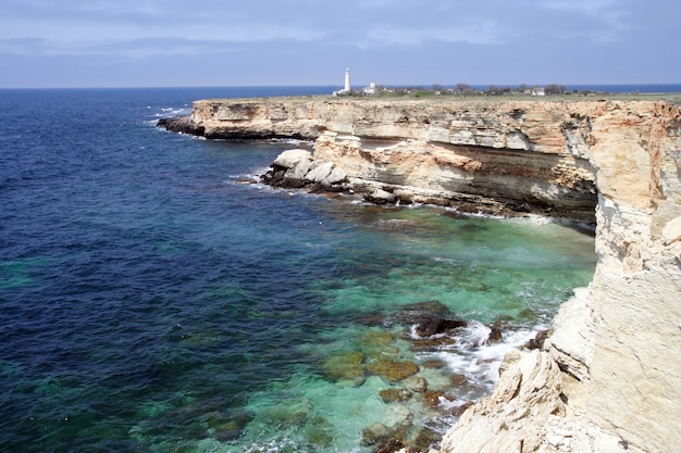 Scogliera rocciosa con il faro in lontananza