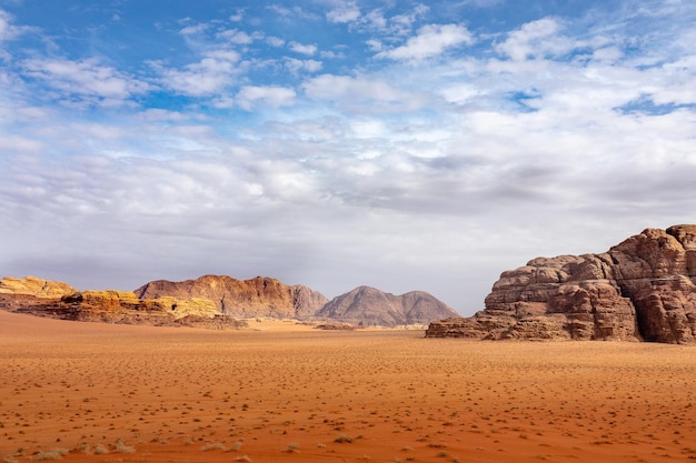 Scogliere e grotte in un deserto pieno di erba secca sotto un cielo nuvoloso durante il giorno