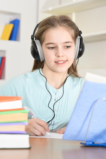 Scolara carina in cuffia che studia a casa