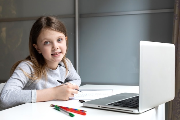 Scolara che fa i compiti con il computer portatile a casa guardando