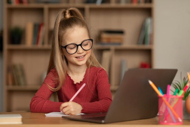 Scolara che impara online usando il laptop e prendendo appunti a casa