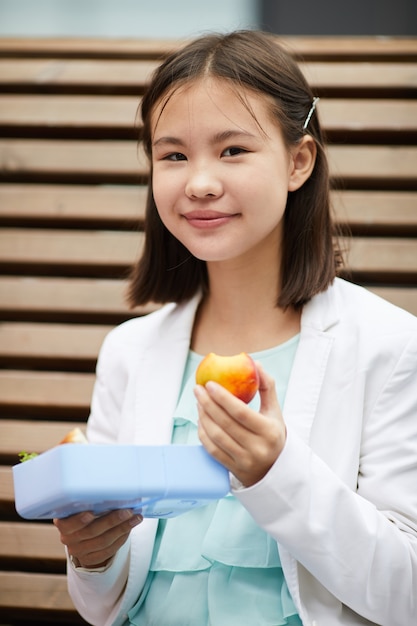 Scolara che mangia frutta durante la pausa a scuola