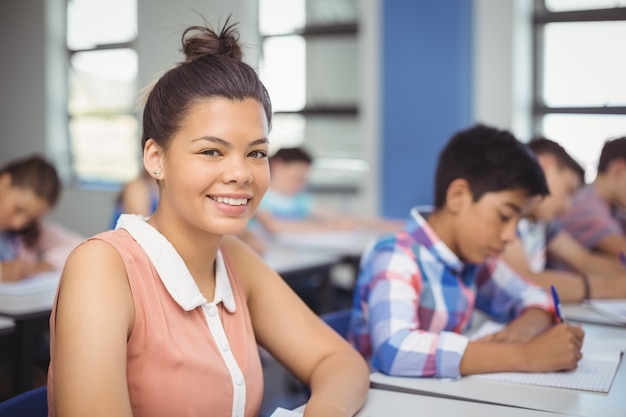 Scolara che si siede allo scrittorio in aula