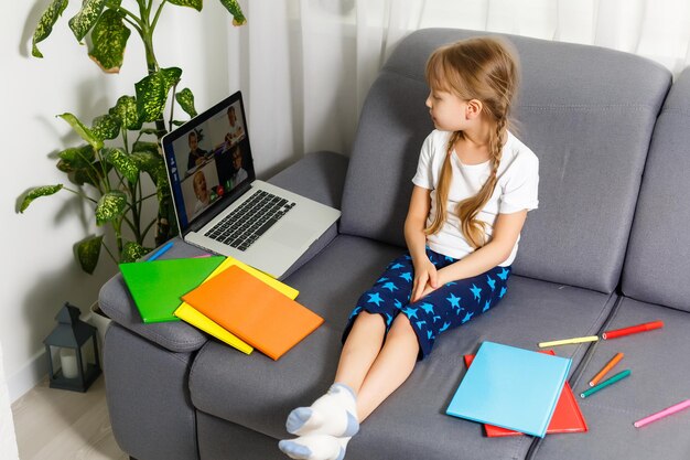 Scolara che studia a casa usando il computer portatile. Scuola a domicilio, istruzione online, istruzione a domicilio, concetto di quarantena - Immagine