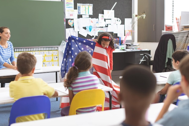 Scolara che tiene bandiera americana in aula