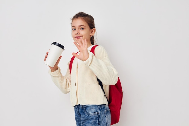 Scolara con uno zaino rosso un bicchiere con un drink in mano