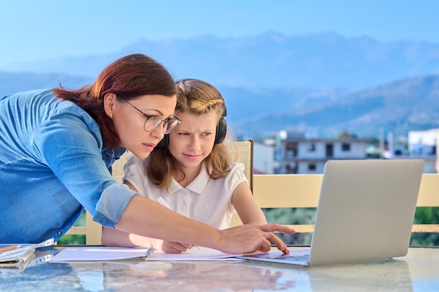 Scolara del bambino che impara online con l'aiuto della mamma del computer portatile