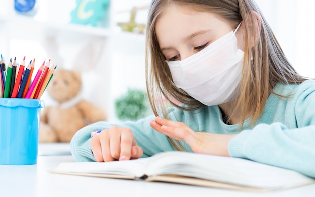 Scolara nella maschera che studia a casa