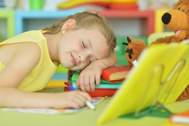 Scolara stanca sveglia che dorme dopo aver fatto i compiti in classe