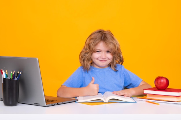 Scolaretto che studia in classe alla scuola elementare Capretto che studia a lezione su sfondo giallo isolato