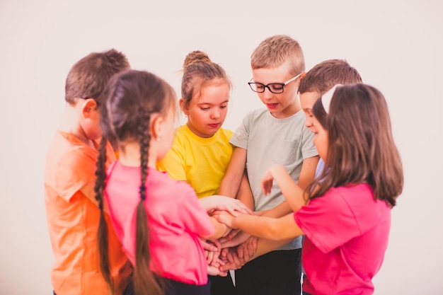 Scolari che tengono le mani insieme in piedi strettamente in cerchio su sfondo bianco Bambini che fanno un accordo Bambini cresciuti abbastanza per comunicare come adulti