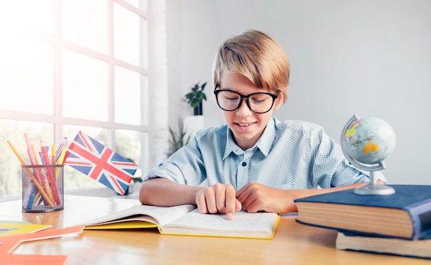 Scolaro adolescente diligente con gli occhiali che si prepara per l'esame nel libro di lettura inglese