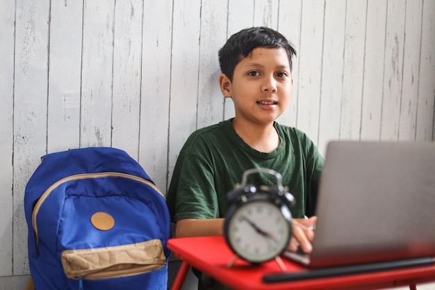 Scolaro asiatico che studia a casa utilizzando un laptop e studia online con l'insegnante di videochiamata a casa.