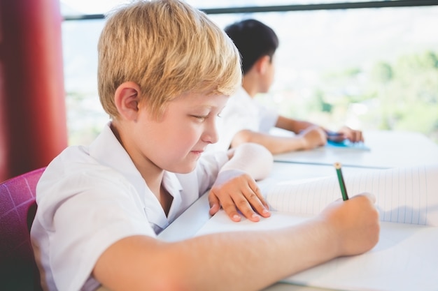 Scolaro che fa i compiti in aula