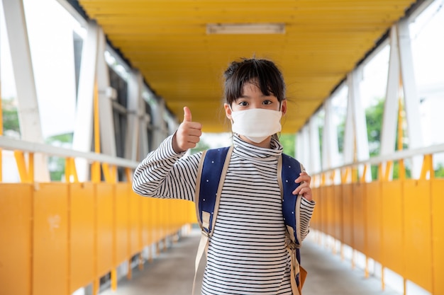 Scolaro che indossa una maschera facciale durante l'epidemia di coronavirus Bambina che torna a scuola