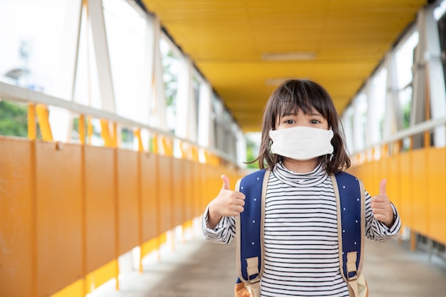 Scolaro che indossa una maschera facciale durante l'epidemia di coronavirus Bambina che torna a scuola