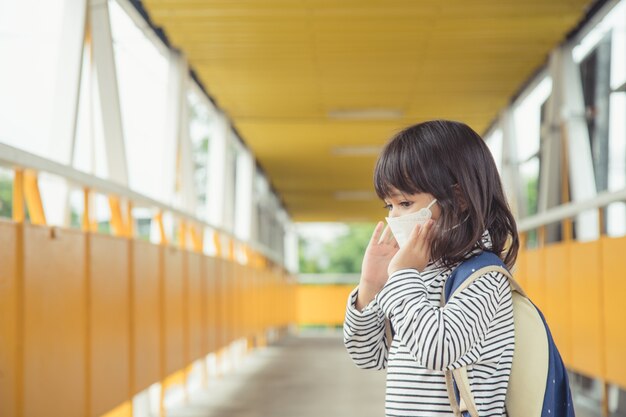 Scolaro che indossa una maschera facciale durante l'epidemia di coronavirus Bambina che torna a scuola