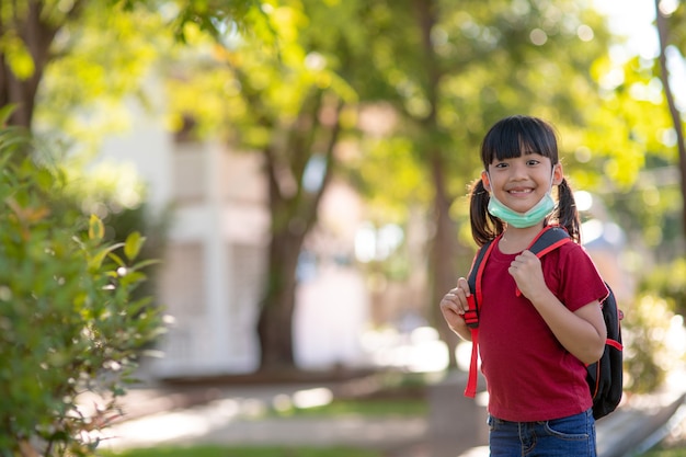 Scolaro che indossa una maschera facciale durante l'epidemia di coronavirus e influenza. sorellastra che torna a scuola dopo la quarantena e il blocco del covid-19. Bambini in maschera per la prevenzione del coronavirus.Soft Focus