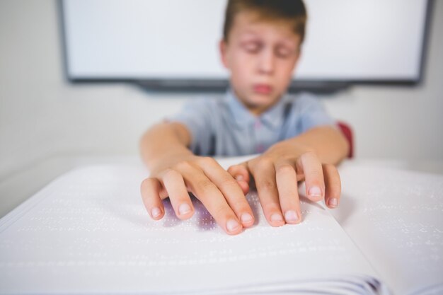 Scolaro che legge un libro di Braille in aula