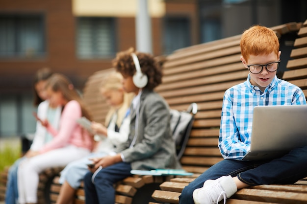 Scolaro che per mezzo del computer portatile all'aperto