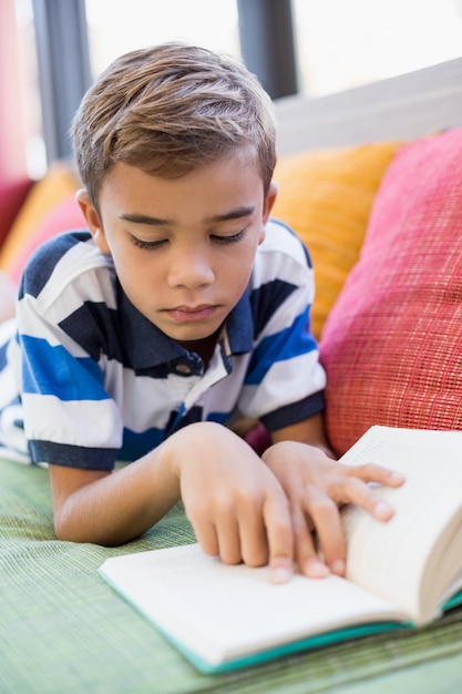 Scolaro che si trova sul sofà e sul libro di lettura